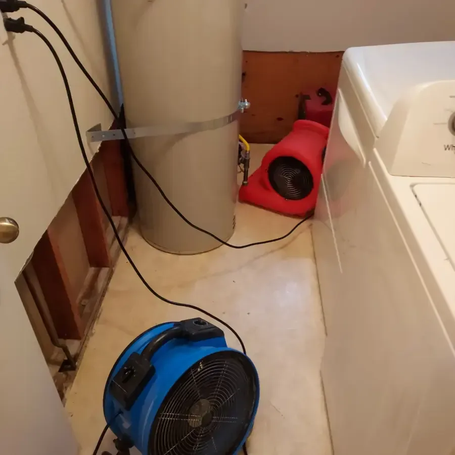 Air movers drying a laundry area with the wall opened behind the washer, an appliance leak dry-out