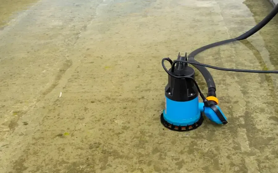 Submersible pump removing standing water from a wet concrete floor